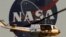 A female Osprey and one of her three chicks are seen against the backdrop of the NASA logo on the Vehicle Assembly Building at the Kennedy Space Center, Saturday, April 3, 2010, in Cape Canaveral, Fla. Space Shuttle Discovery is scheduled to launch Monday