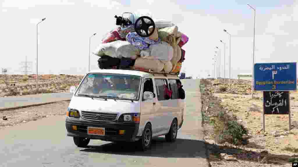 Vans packed with people fleeing Libya with whatever they could take, February 23, 2011. (VOA Photo/E. Arrott)