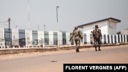 Deux militaires centrafricains patrouillent dans le quartier désert du PK12, à 12 kilomètres du centre-ville de Bangui, où les combats ont fait rage contre les rebelles de la Coalition des Patriotes pour le Changement (CPC) et les forces loyalistes, à Bangui, le 13 janvier 2021.