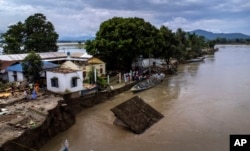 Villagers watch a temple of Hindu goddess Durga being washed away at Murkata village, Thursday, Oct. 13, 2022.