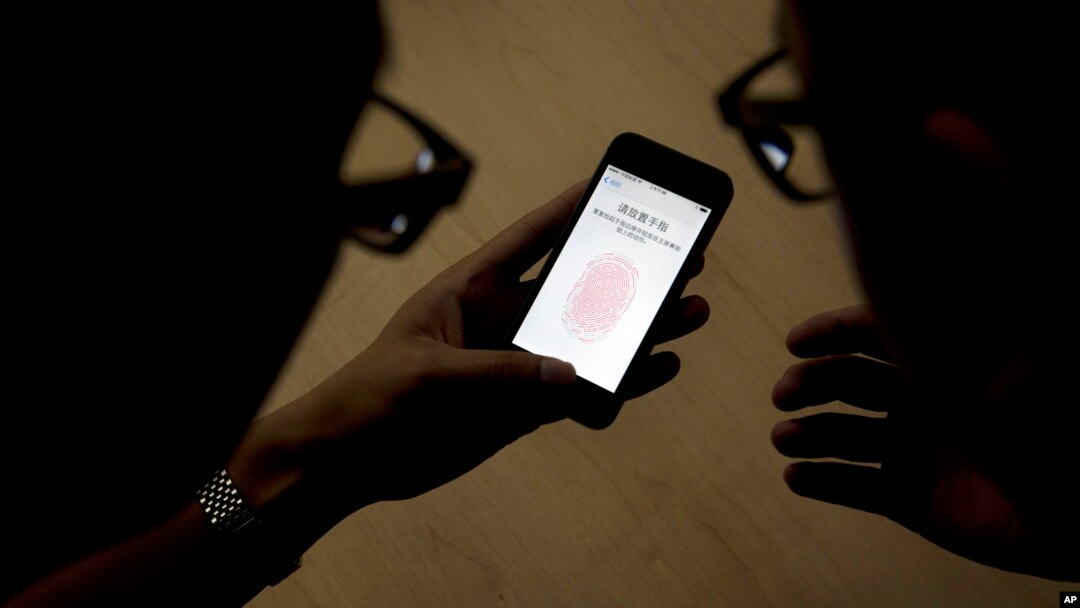 FILE - Apple employee, right, instructs a journalist on the use of the fingerprint scanner technology built into the company's iPhone 5S during a media event in Beijing. 