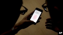 FILE - Apple employee, right, instructs a journalist on the use of the fingerprint scanner technology built into the company's iPhone 5S during a media event in Beijing. 