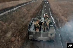 In this photo taken from video released by the Russian Defense Ministry Press Service on April 13, 2024, Russian soldiers ride their armored vehicle to take positions and fire toward Ukrainian positions at an undisclosed location in Ukraine.