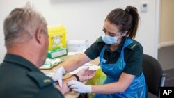 La paramédico Jess Baddams toma una muestra de sangre de Tony Oliver durante una prueba para el coronavirus en Birmingham, Inglaterra.