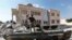 FILE - A Free Syrian Army soldier stands on a Syrian military tank in front of a mosque, which were damaged during fighting with government forces, in the Syrian town of Azaz, on the outskirts of Aleppo, Sept. 23, 2012.