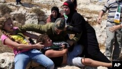 FILE - In this Aug, 28, 2015 photo, Palestinian women and girls scuffle with an Israeli soldier trying to arrest a 12-year-old boy during a protest near the West Bank village of Nebi Saleh.
