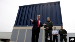 FILE - President Donald Trump speaks during a tours as he reviews border wall prototypes, March 13, 2018, in San Diego, as Rodney Scott, the Border Patrol's San Diego sector chief, listens. 