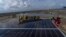 FILE - Workers install solar panels at the under-construction Adani Green Energy Limited's Renewable Energy Park in the salt desert of Karim Shahi village, near Khavda, Bhuj district near the India-Pakistan border in the western state of Gujarat, India, Sept. 21, 2023. 