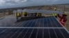 (FILE) Workers install solar panels in the salt desert of Karim Shahi village, in India, on Sept. 21, 2023.