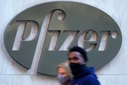 Dos personas pasan por el edificio de la sede de Pfizer.