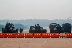 Myanmar's military stand guard at a checkpoint manned with an armored vehicles blocking a road leading to the parliament building, Feb. 2, 2021, in Naypyitaw, Myanmar.