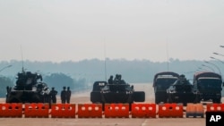 FILE - Myanmar's military stand guard at a checkpoint manned with an armored vehicles blocking a road leading to the parliament building, Feb. 2, 2021, in Naypyitaw. 