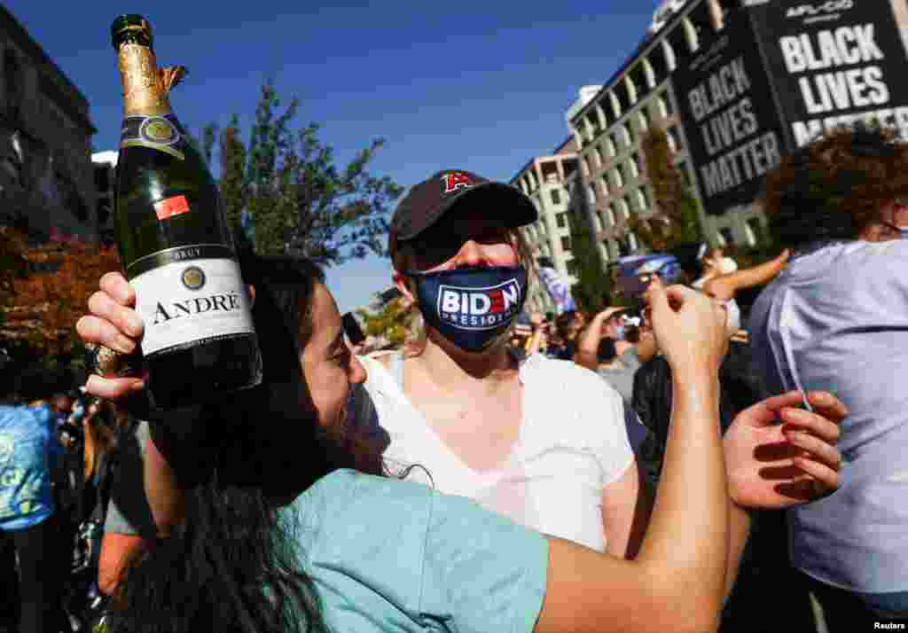 People react after media announced that Democratic U.S. presidential nominee Joe Biden has won the 2020 U.S. presidential election, on Black Lives Matter Plaza near the White House, in Washington.