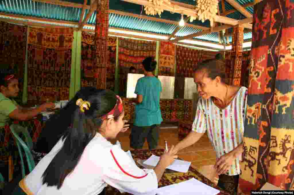 Petugas Tempat Pemungutan Suara (TPS) 05 di Kelurahan Prailiu, Kecamatan Kambera, Kabupaten Sumba Timur, membantu seorang pemilih dalam pemilihan Gubernur NTT 2018, 27 Juni 2018. Hari ini, sebanyak 171 daerah melakukan pemilihan kepala daerah secara serentak. Nusa Tenggara Timur NTT Pemilihan Gubernur NTT 2018. (Courtesy Photo: Heinrich Dengi)