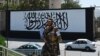 A member of the Taliban's Fateh, a special forces unit, stands guard outside the U.S. embassy in Afghanistan, now with a Taliban flag painted on in its outer concrete wall, in Kabul, Sept. 8, 2021. 