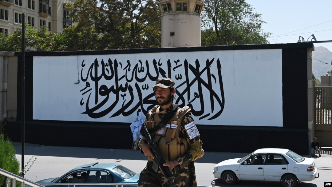 FILE - A member of the Taliban's Fateh, a special forces unit, stands guard outside the U.S. embassy in Afghanistan, now with a Taliban flag painted on its outer concrete wall, in Kabul, Sept. 8, 2021. 