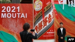 FILE - People take photos outside the stand for Kweichow Moutai, a Chinese liquor brand, at the China Food and Drinks fair in Chengdu, in China's southwest Sichuan province, April 4, 2021.