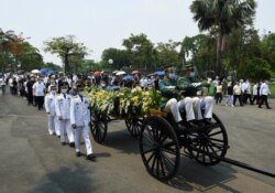 Philippine military officers and honor guards, together with family members, march alongside the carriage carrying the urn of the late president Benigno Aquino during the inurnment at a memorial park in Manila on June 26, 2021.