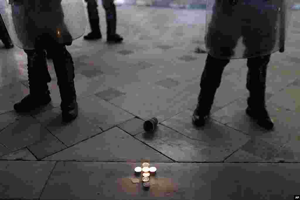 Candles forming a cross sit in front of the tomb of the unknown soldier as riot police secure the Greek Parliament, during a protest in Athens, April 4, 2012.  (AP)