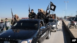 In this photo released on May 4, 2015, by a militant website, which has been verified and is consistent with other AP reporting, Islamic State militants pass by a convoy in Tel Abyad town, northeast Syria.