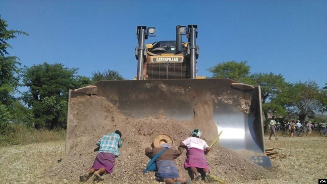 Para penduduk desa Myanmar barbering di depan sebuah bulldozer untuk memprotes ekspansi perusahaan pertambangan tembaga Lepadaung yang didukung China (22/12).