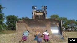 Para penduduk desa Myanmar barbering di depan sebuah bulldozer untuk memprotes ekspansi perusahaan pertambangan tembaga Lepadaung yang didukung China (22/12).