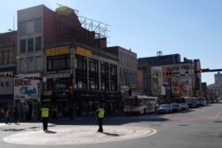 Newark police officers, encouraging people to practice social distancing, patrol an intersection in Newark, N.J., March 26, 2020.