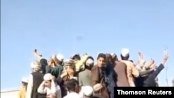칸다하르시의 일부 주민들이 탈레반 무장 행렬을 지켜보고 있다.