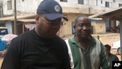 FrontPage Africa editor Rodney Sieh (left) escorted by a marshal (right)