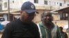 FrontPage Africa editor Rodney Sieh (left) escorted by a marshal (right)