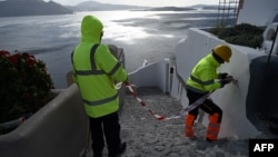 Enpleados municipales colocan cintas de advertencia para restringir el acceso de los turistas, como medida de precaución por la reciente actividad sísmica en la zona de Oia, en la isla griega de Santorini, el 5 de febrero de 2025.