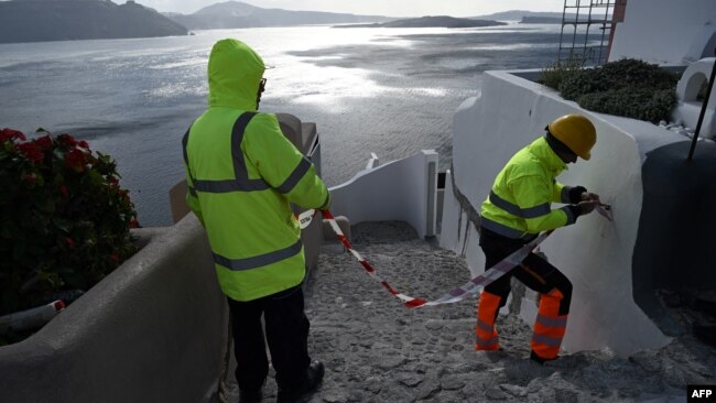Enpleados municipales colocan cintas de advertencia para restringir el acceso de los turistas, como medida de precaución por la reciente actividad sísmica en la zona de Oia, en la isla griega de Santorini, el 5 de febrero de 2025.