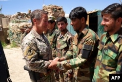 FILE - Gen. Scott Miller, commander of U.S. and NATO forces in Afghanistan shakes hands with Afghan National Army soldiers during a visit at a checkpoint in Nerkh district of Wardak province in west Kabul, June 6, 2019.