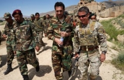 In this photo taken on June 6, 2019, commander of US and NATO forces in Afghanistan General Austin Scott Miller, right, walks with Afghanistan's acting Defense Minister Asadullah Khalid, center.