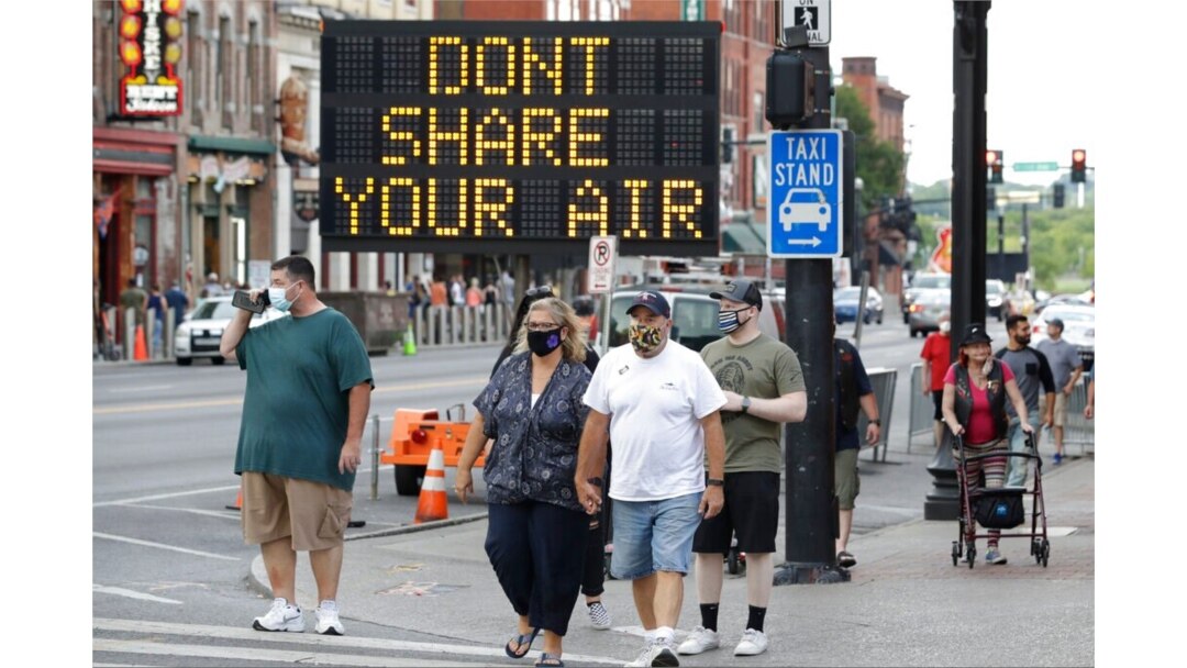 FILE - A sign encouraging the wearing of masks and adhering to social distancing stands at a street corner in downtown Nashville, Tenn., Aug. 5, 2020.