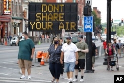 FILE - A sign encouraging the wearing of masks and keeping social distancing stands at a street corner in downtown Nashville, Tenn., Aug. 5, 2020.