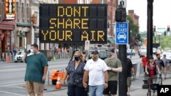 FILE - A sign encouraging the wearing of masks and keeping social distancing stands at a street corner in downtown Nashville, Tenn., Aug. 5, 2020.
