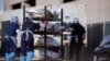 FILE - El Paso County Medical Examiner's Office staff roll bodies that are in bags labeled "Covid" from refrigerated trailers into the morgue office amid the COVID-19 outbreak, in El Paso, Texas, Nov. 23, 2020.