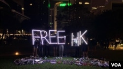 香港民眾11月9日晚在添馬公園舉行集會，悼念不幸去世的香港科技大學學生周梓樂。活動結束後，有民眾撐起Free HK（自由香港）字樣的燈光。（美國之音林楓拍攝）