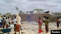 FILE - People walk through rubble after U.S. warplanes killed an Islamist rebel said to be an al-Shabab leader in Somalia, May 1, 2008.