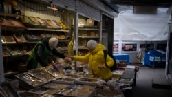 Seorang perempuan tampak membeli produk dari seorang pedagang di sebuah pasar di Kyiv, Ukraina, pada 30 Januari 2023. (Foto: AP/Daniel Cole)