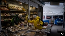 Seorang perempuan tampak membeli produk dari seorang pedagang di sebuah pasar di Kyiv, Ukraina, pada 30 Januari 2023. (Foto: AP/Daniel Cole)