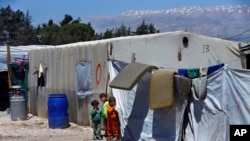 FILE - Syrian refugee children stand next to their family tents at a refugee camp in the town of Bar Elias, in Lebanon's Bekaa Valley, April 23, 2018. 