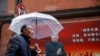 A man walks with an umbrella past a picture of Chinese President Xi Jinping on a street ahead of the National People's Congress (NPC), in Shanghai, March 2, 2021.