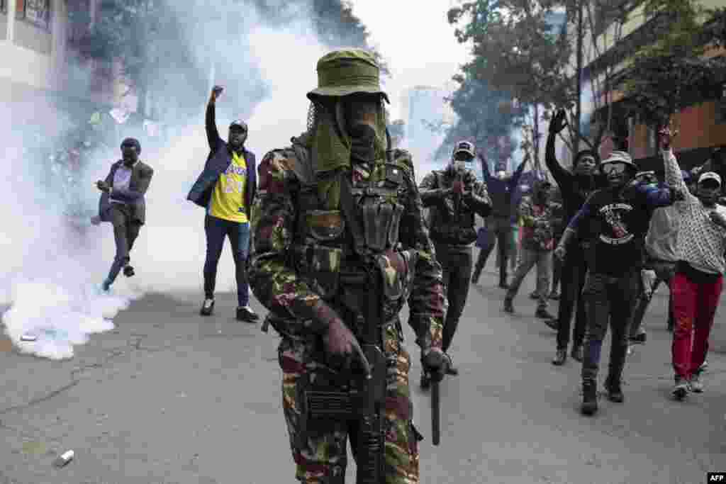 Manifestantes confrontam um agente da polícia queniana anti-motim durante uma manifestação contra o aumento dos impostos, enquanto os deputados continuam a debater a Lei das Finanças de 2024 no centro de Nairobi, a 20 de junho de 2024.