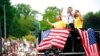 Olympian Sunisa Lee, center, waves from a St. Paul fire truck with her mom Yeev Thoj, left, and sister Shyenne Lee as fans cheer for her along the White Bear Ave. parade route, Sunday, Aug. 8, 2021, in St. Paul, Minn. Minnesota celebrated the Olympic…