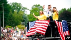 Olympian Sunisa Lee, center, waves from a St. Paul fire truck with her mom Yeev Thoj, left, and sister Shyenne Lee as fans cheer for her along the White Bear Ave. parade route, Sunday, Aug. 8, 2021, in St. Paul, Minn. Minnesota celebrated the Olympic…