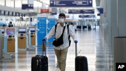 Un viajero usa mascarilla y gafas protectoras mientras camina por la Terminal 3 en el Aeropuerto Internacional O'Hare el martes 16 de junio de 2020 en Chicago.