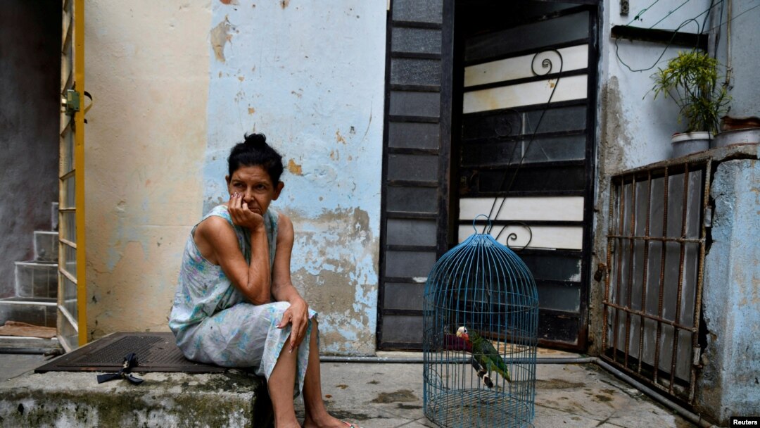 Una mujer se sienta afuera con su loro mientras Cuba sufre un apagón en toda la isla, en La Habana, Cuba, el 18 de octubre de 2024. REUTERS/Norlys Perez.