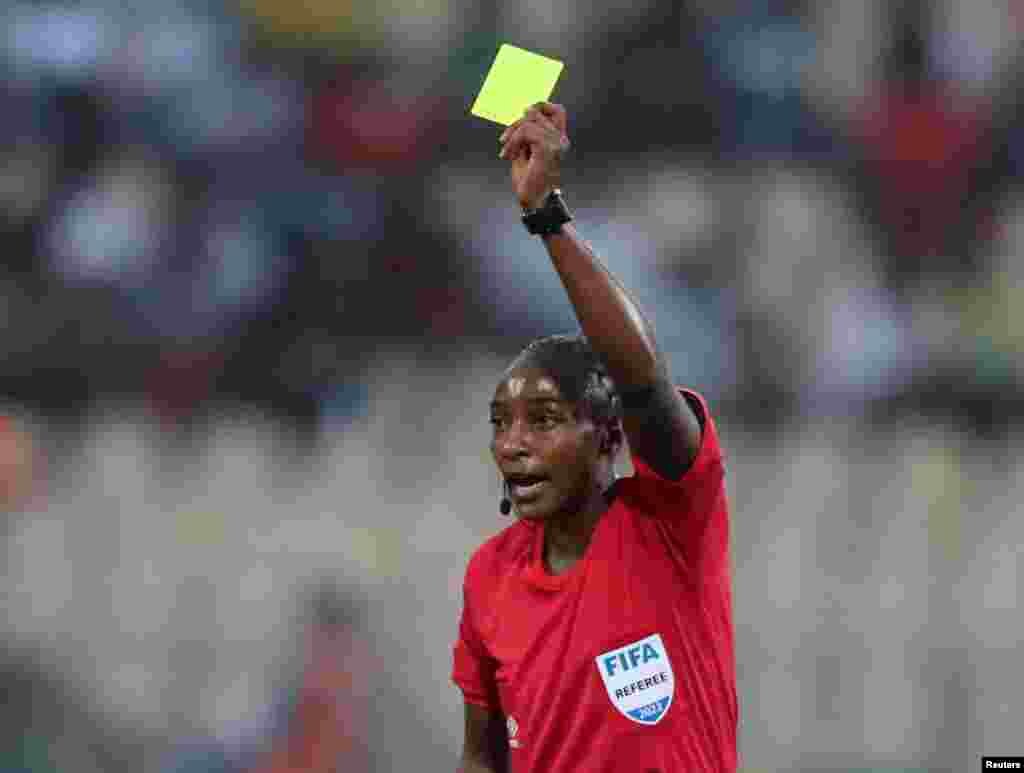 Referee Salima Mukansanga shows a yellow card to Zimbabwe&#39;s Talbert Shumba, Cameroon, Jan. 18, 2022.